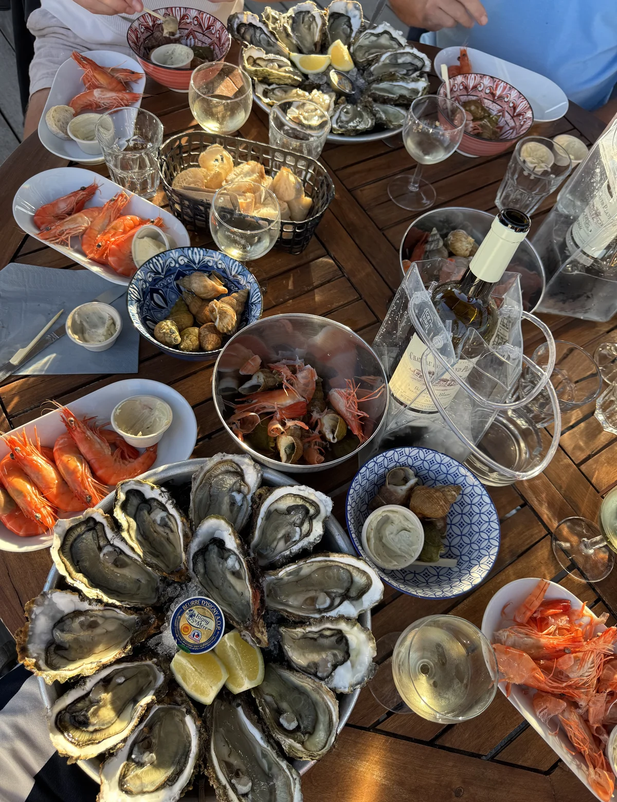 A table set with platters of oysters, prawns and bowls of whelks